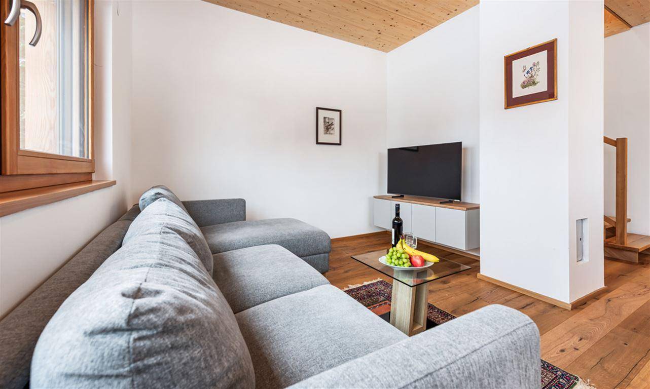 Gemütlicher Wohnbereich mit grauem Sofa, Couchtisch und Fernseher.