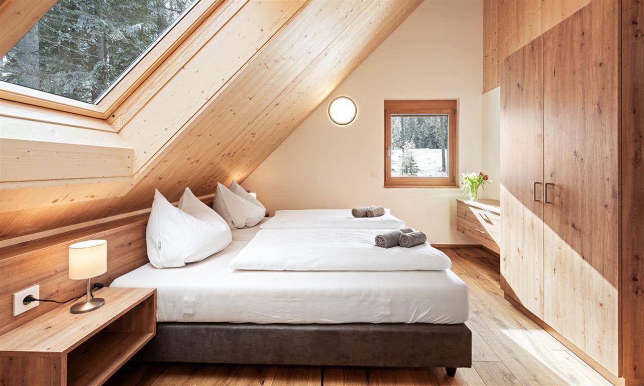 Schlafzimmer mit Doppelbett, Holzschrank, Dachfenster und Holzboden.