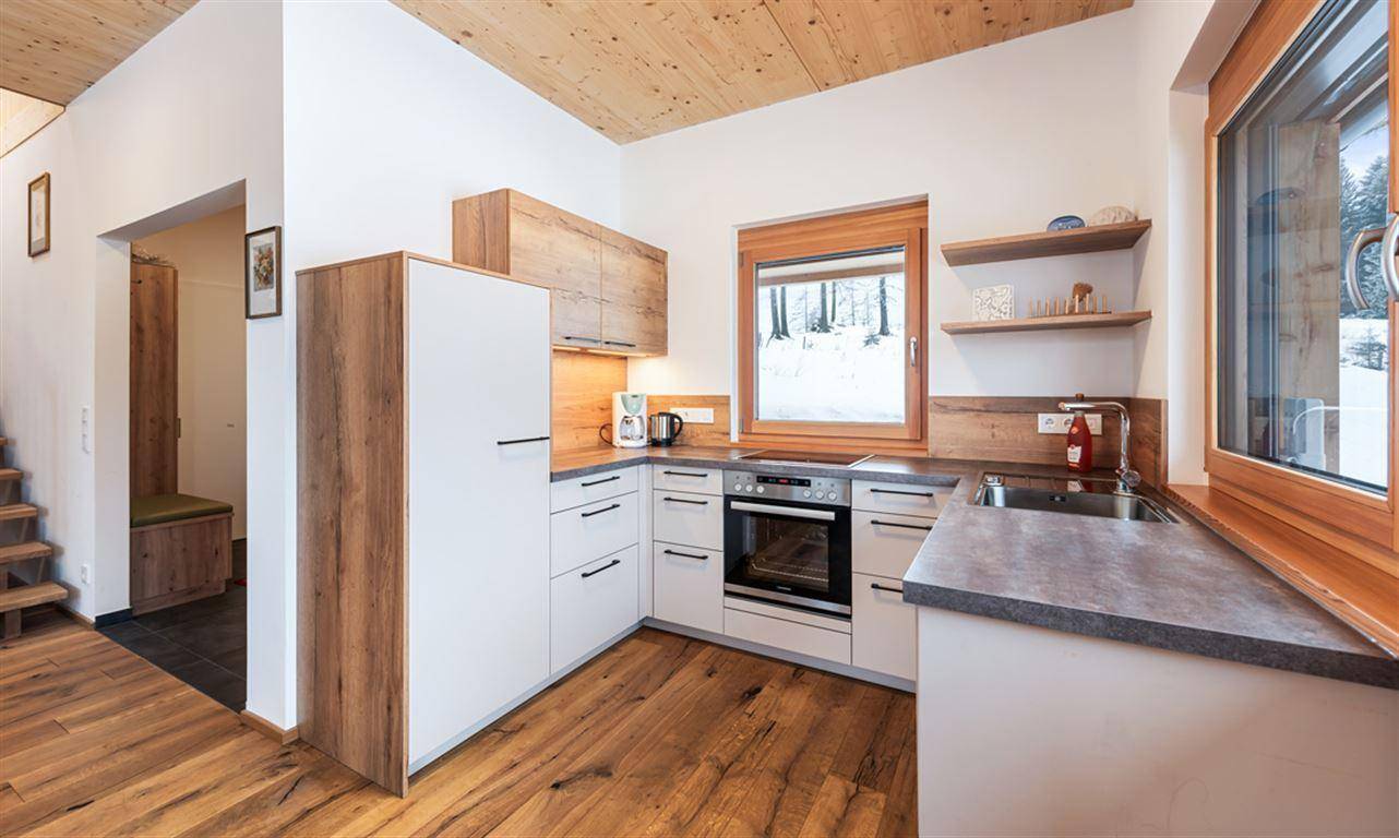 Moderne Küche mit Holzelementen, Einbaugeräten und robustem Holzboden.