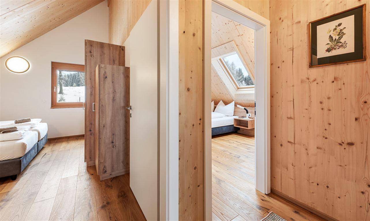 Schlafzimmer mit Holzwänden und Dachschrägen, mit Blick auf die verschneite Landschaft.