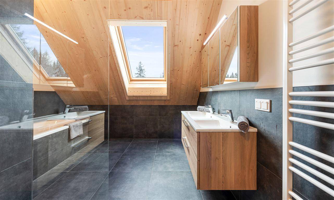 Helles Badezimmer mit Dachfenster, Doppelwaschbecken und Badewanne.