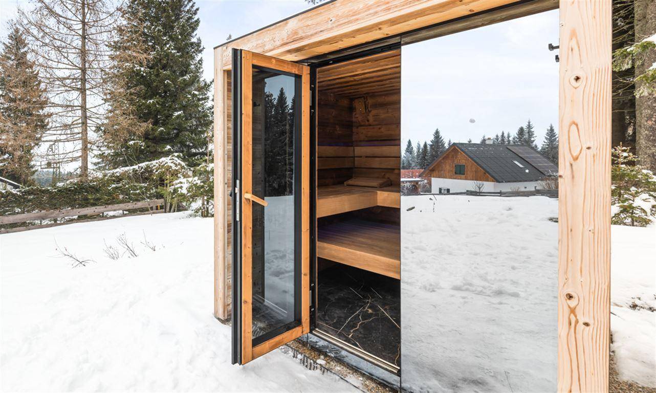 Außensauna mit Holzbänken und Blick auf die verschneite Umgebung.