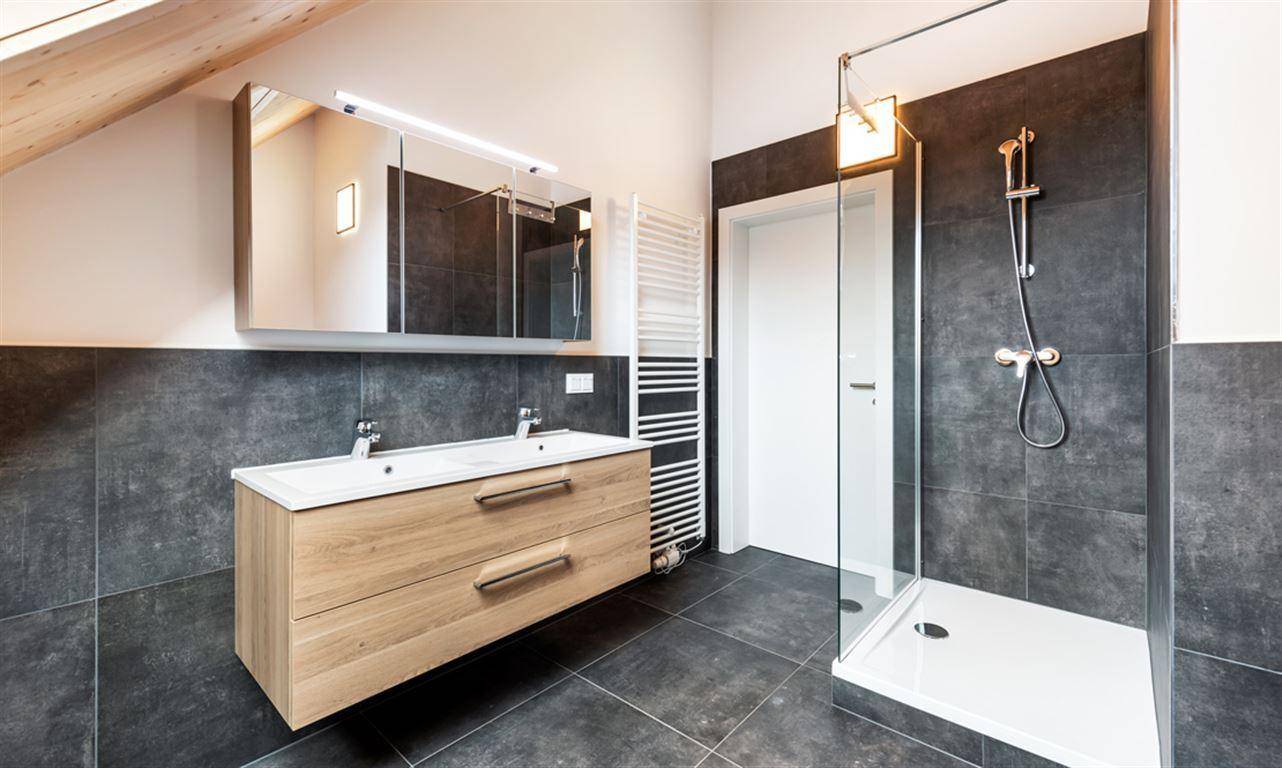 Modernes Badezimmer mit Doppelwaschbecken, Dusche und beheiztem Handtuchhalter.
