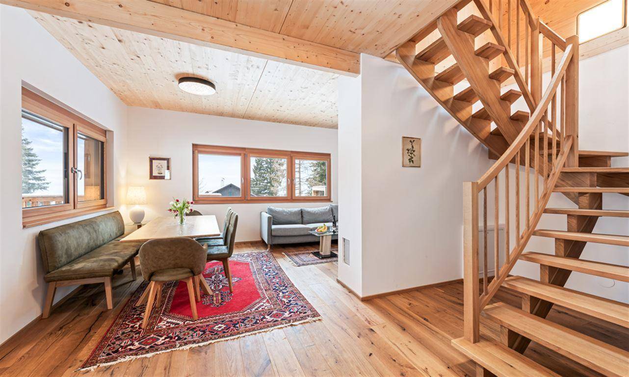 Kombinierter Wohn- und Essbereich mit offener Holztreppe zum Obergeschoss.