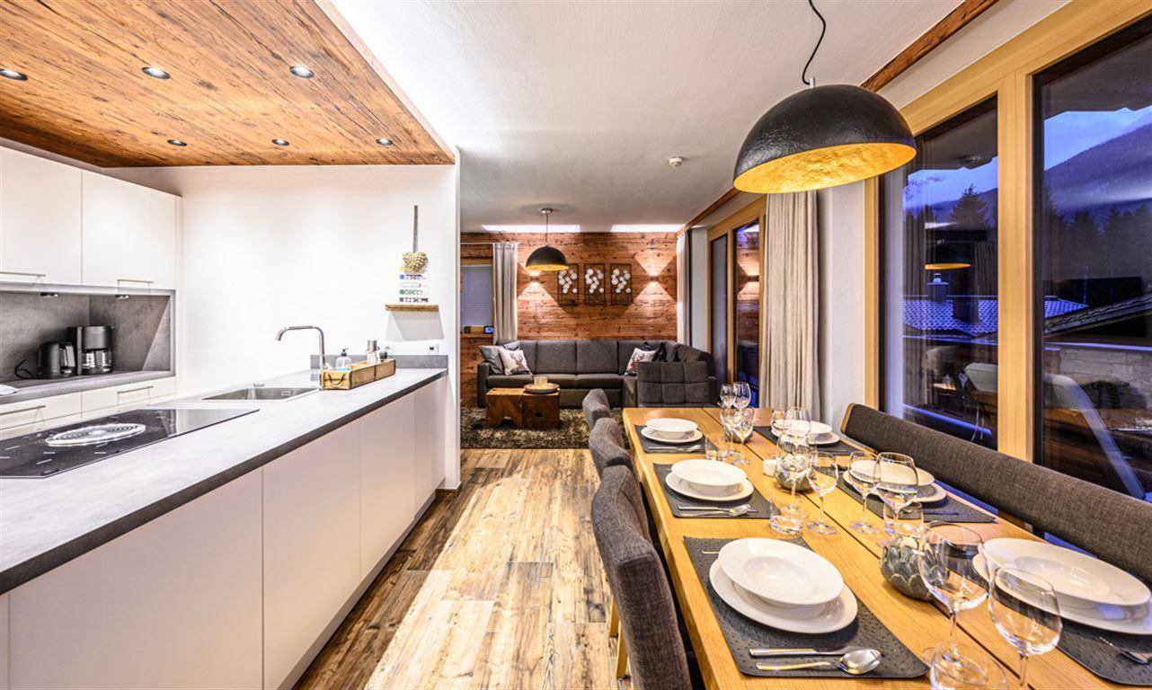 Offene Küche und Essbereich mit Holzboden und Blick auf die Berge, verbunden mit dem Wohnzimmer.