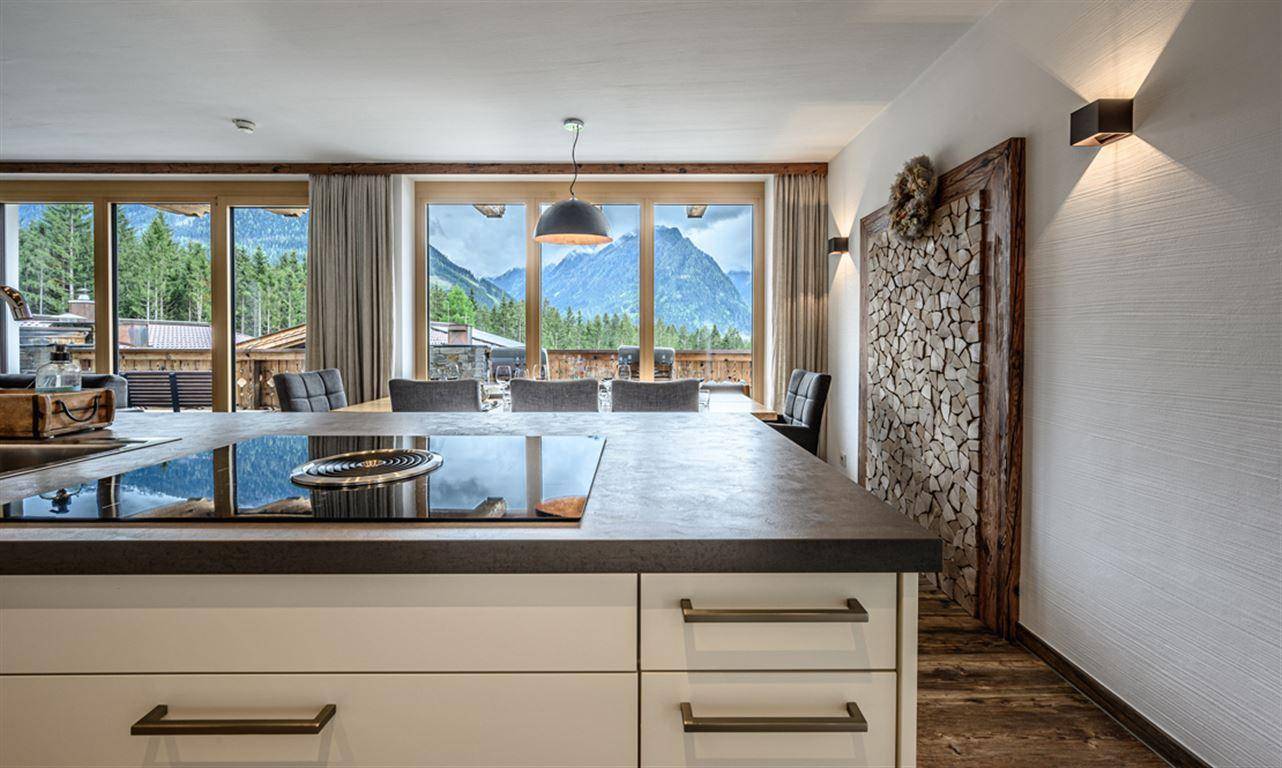 Moderne Küche mit Kochinsel und Bergblick, offen zum Essbereich, ideal für kulinarische Erlebnisse.