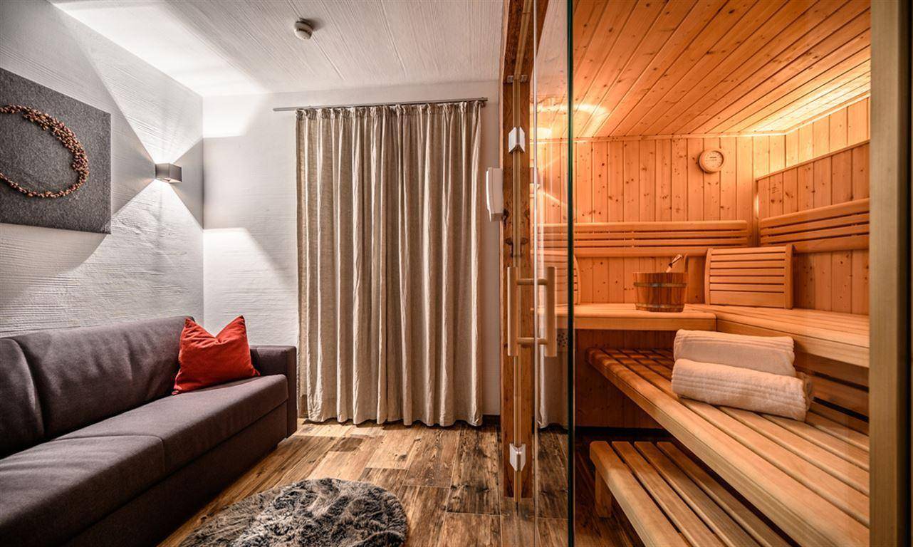 Entspannungsbereich mit Sauna und bequemer Couch, ideal für Wellness und Erholung.