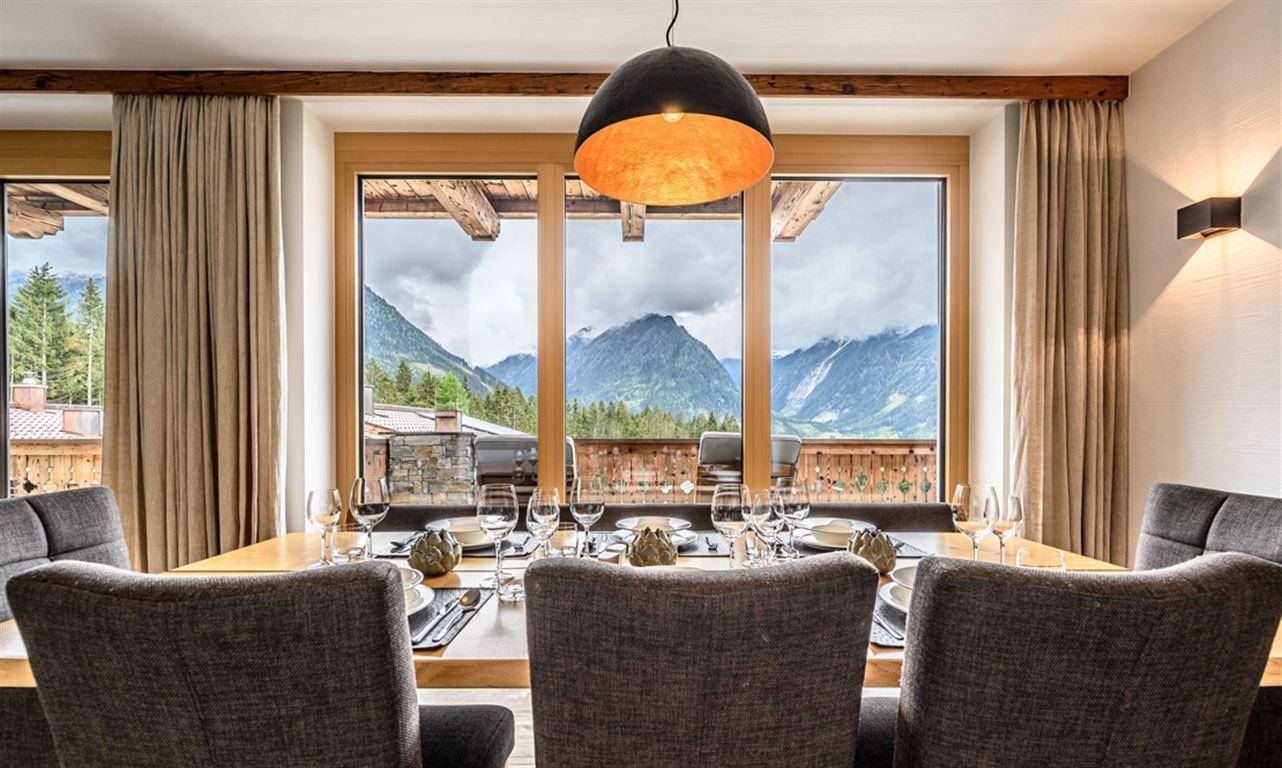 Eleganter Essbereich mit großem Holztisch und Stühlen, bietet einen atemberaubenden Bergblick.