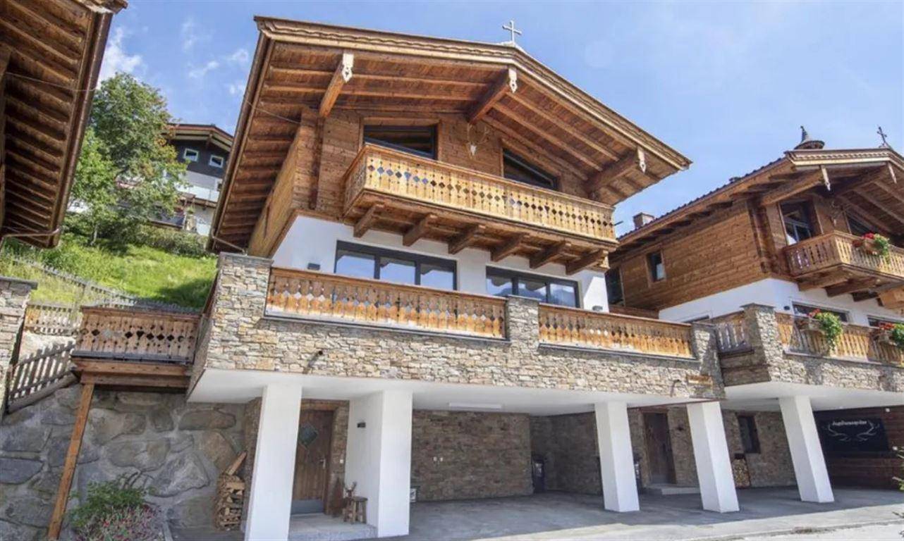 Traditionelles Holzchalet mit Steinfassade und Balkonen, eingebettet in die alpine Landschaft.