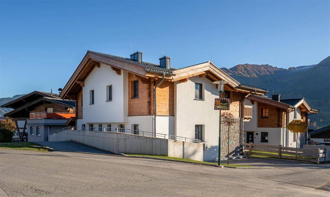 Modernes Wohnhaus mit weißer Fassade, Holzverkleidung und barrierefreier Rampe im alpinen Stil.