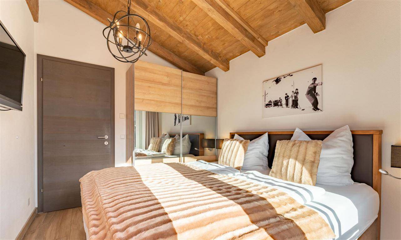 Schlafzimmer mit Holzbalkendecke, Doppelbett und Spiegelschrank für viel Stauraum.