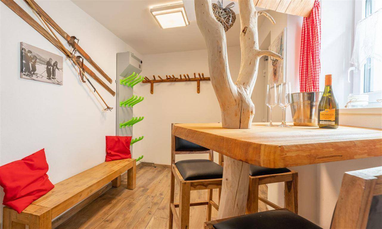 Alpiner Raum mit Bartisch, Holzbänken und praktischer Skiausrüstung-Aufbewahrung.