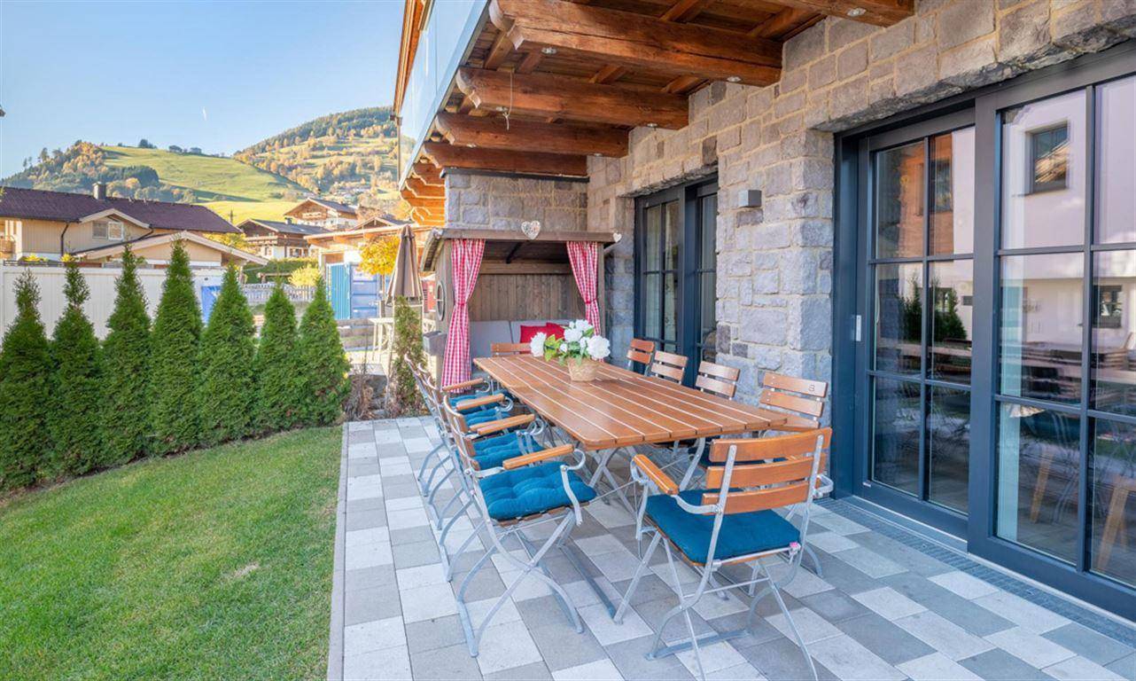 Große gepflasterte Terrasse mit Esstisch, Garten und Blick auf die umliegende Landschaft.
