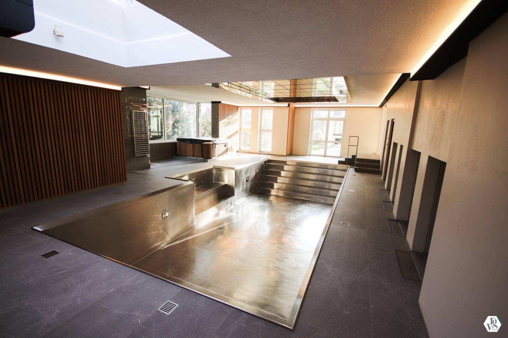 Geräumiger Innenpoolbereich mit Oberlichtern und großen Fenstern, die viel Tageslicht in den Wellnessbereich bringen.