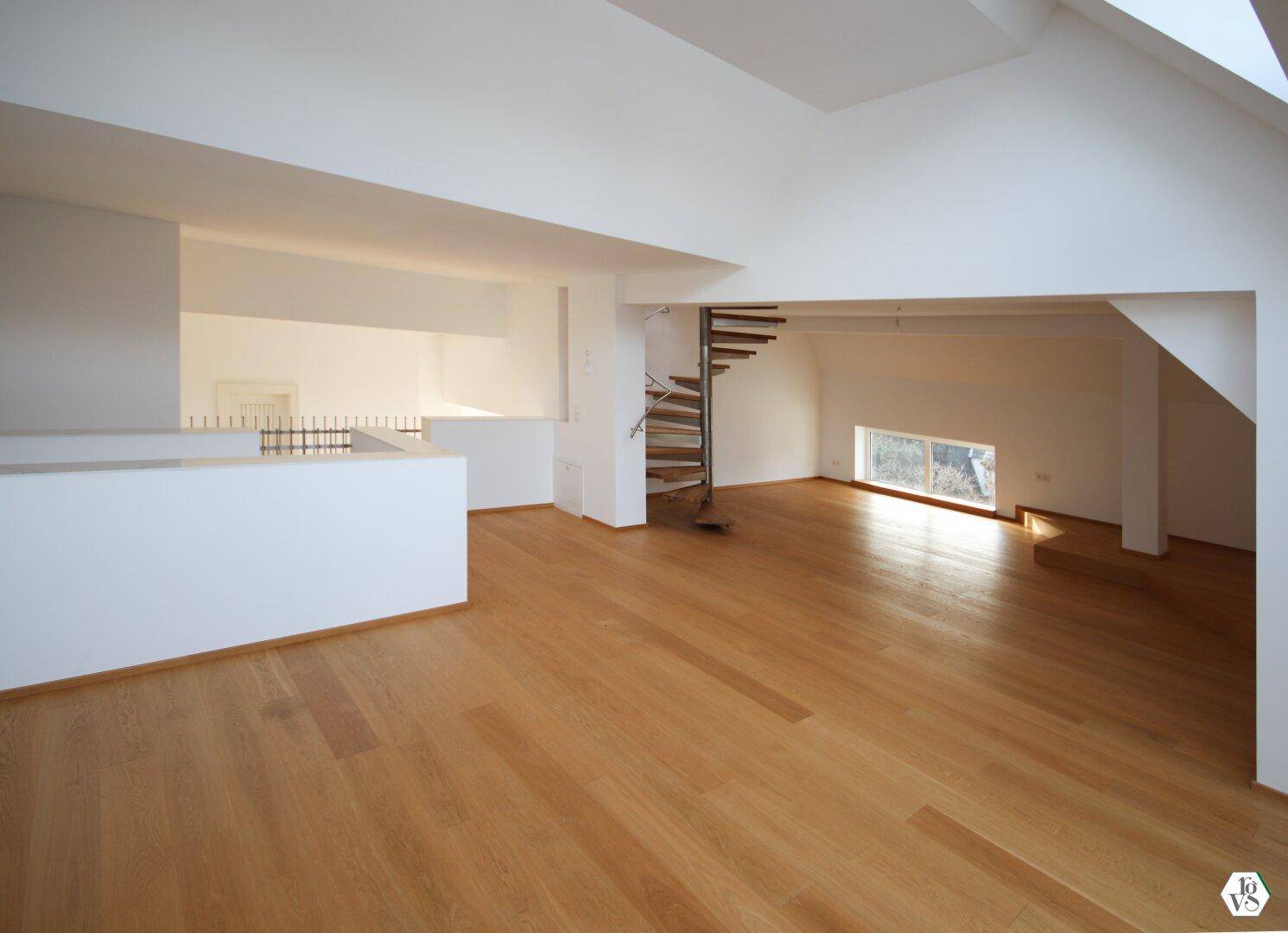 Offener Wohnbereich mit Wendeltreppe und Holzboden, der eine Verbindung zu weiteren Ebenen schafft.