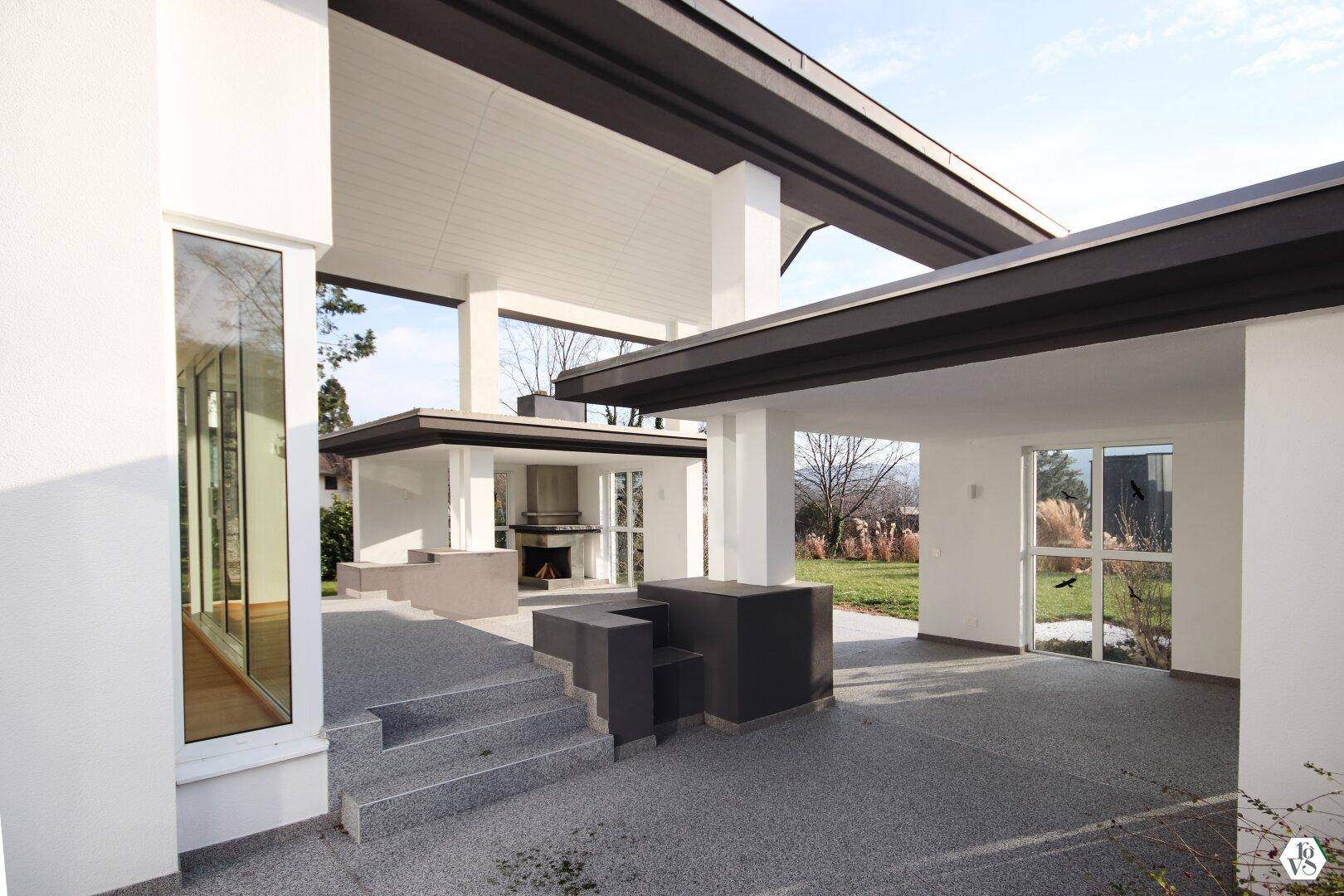 Überdachte Terrasse mit integriertem Grillbereich und Blick ins Grüne, ideal für gesellige Stunden im Freien.