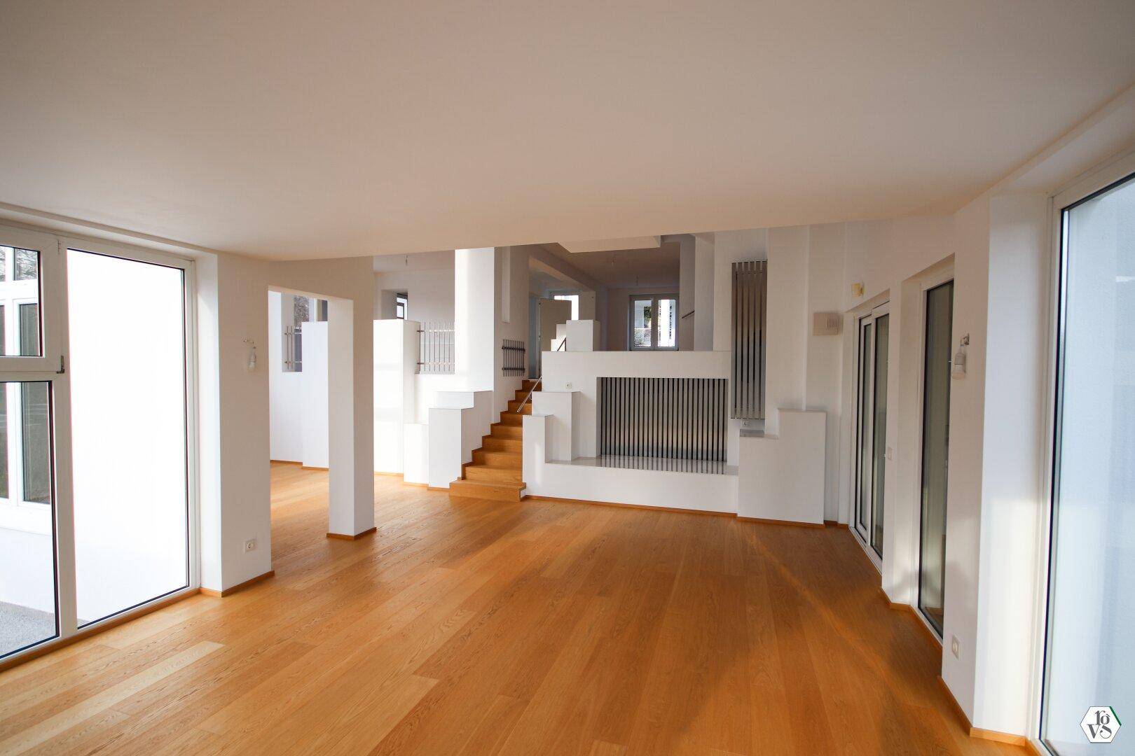 Geräumiger, heller Wohnbereich mit hochwertigem Parkettboden und Zugang zu den Außenbereichen durch große Türen.