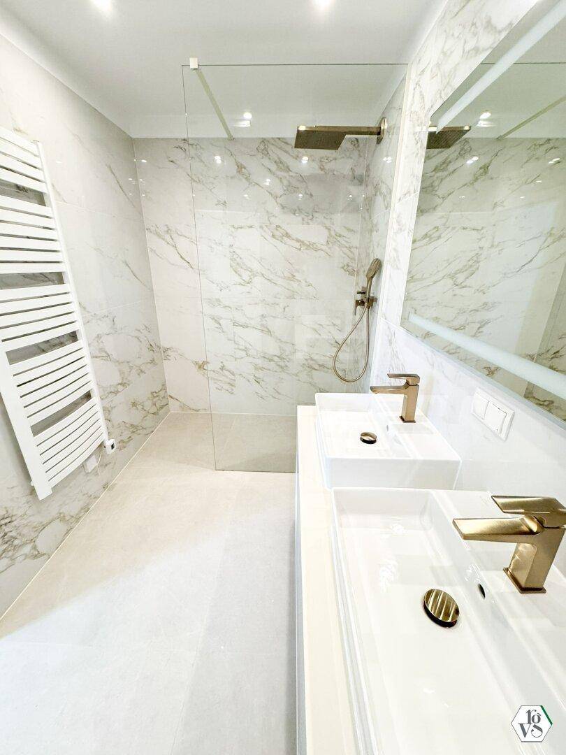 Modernes Badezimmer mit doppelten Waschbecken, großer begehbarer Dusche und eleganten Marmorfliesen.