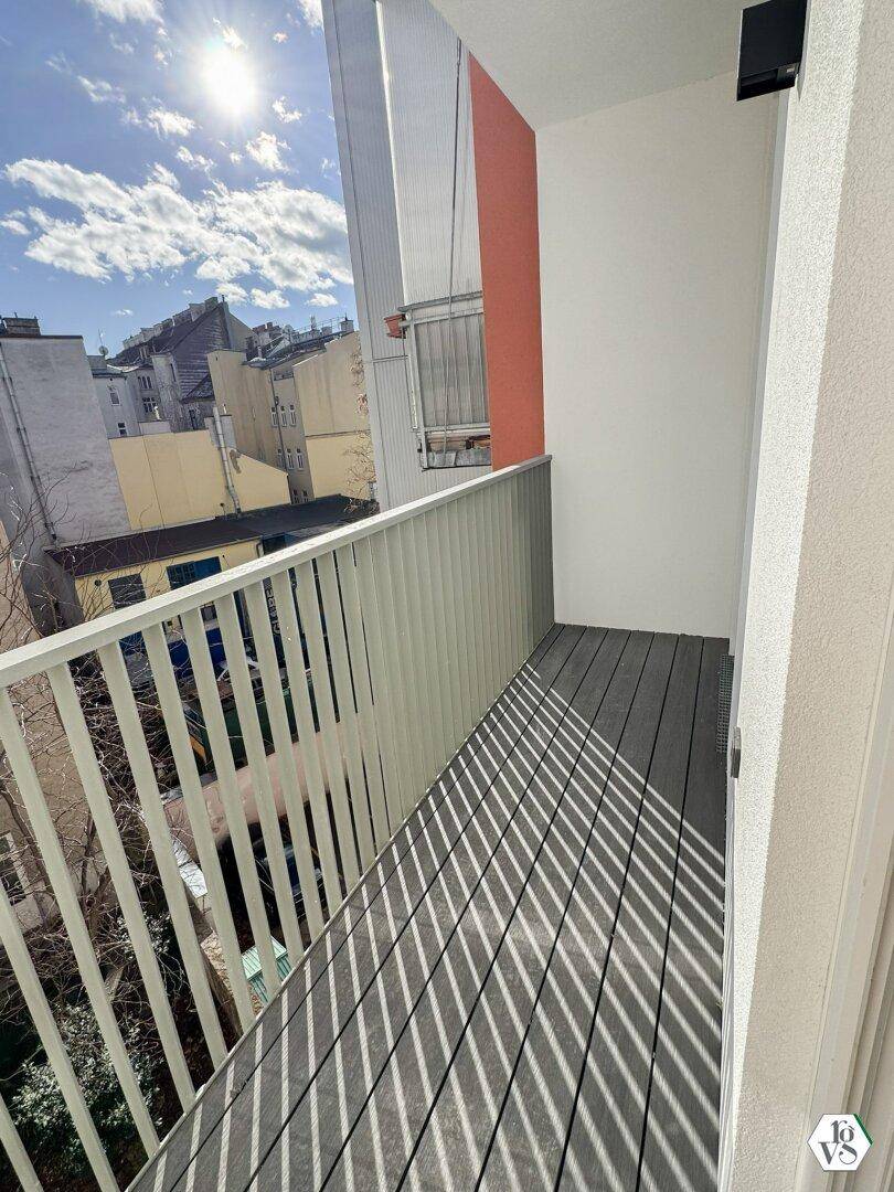 Sonniger Balkon mit modernem Geländer und Blick auf die umliegenden Stadtgebäude.