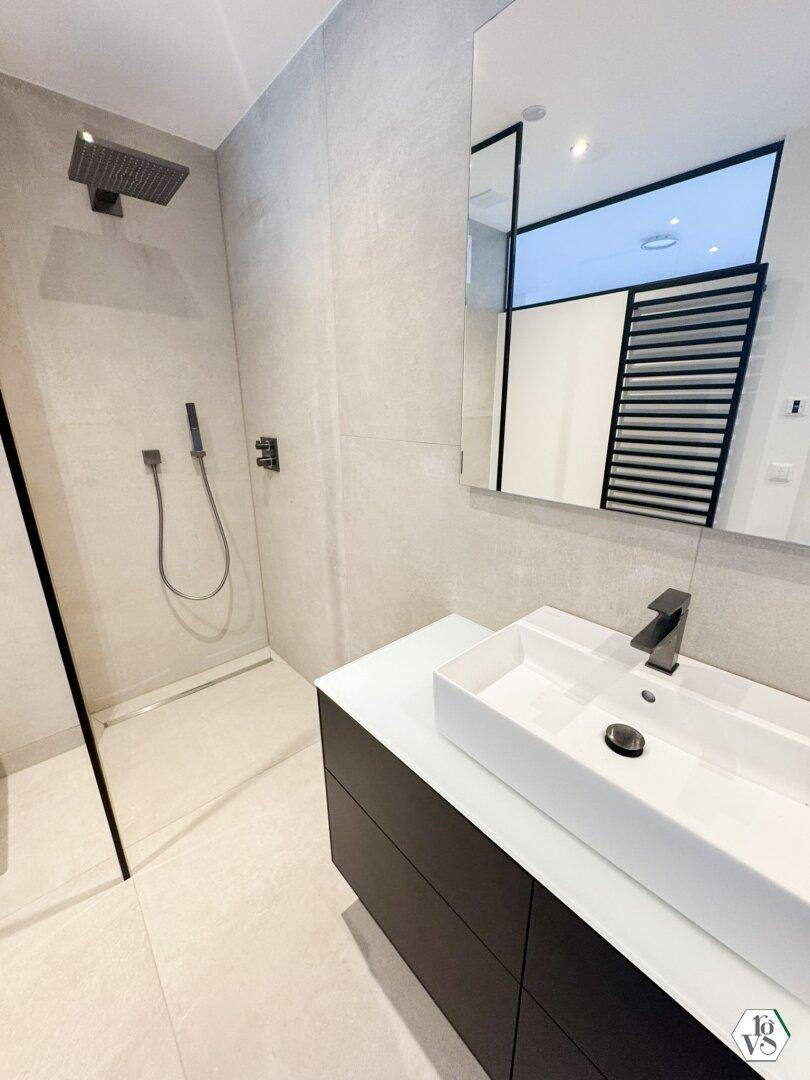 Modernes Badezimmer mit begehbarer Dusche, Einzelwaschbecken und beheiztem Handtuchhalter.