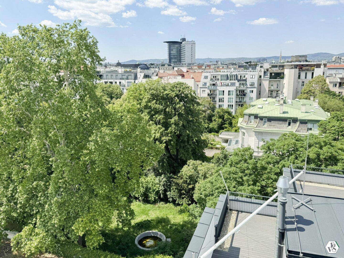 Panoramablick von der Dachterrasse auf die umliegenden grünen Gärten und die Stadtlandschaft.