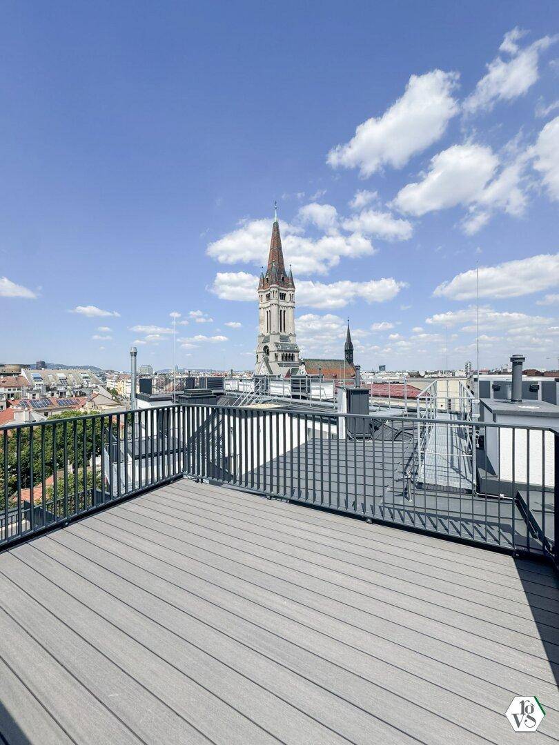 Dachterrasse mit beeindruckendem Stadtblick, inklusive historischer Kirchturmspitze und weitem Horizont.