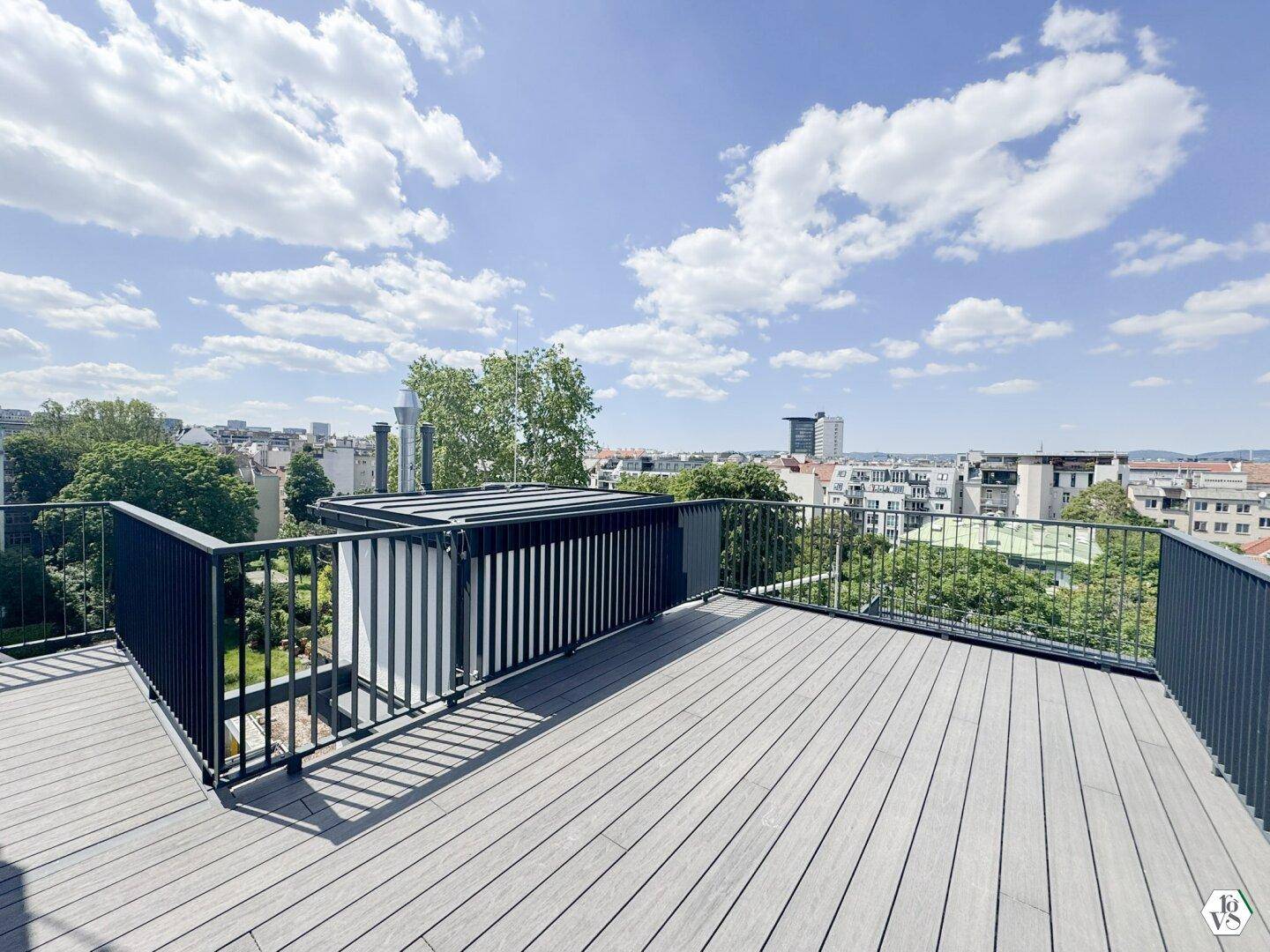 Weitläufige Dachterrasse mit Holzoptik-Boden und Panoramablick auf die Stadt unter blauem Himmel.