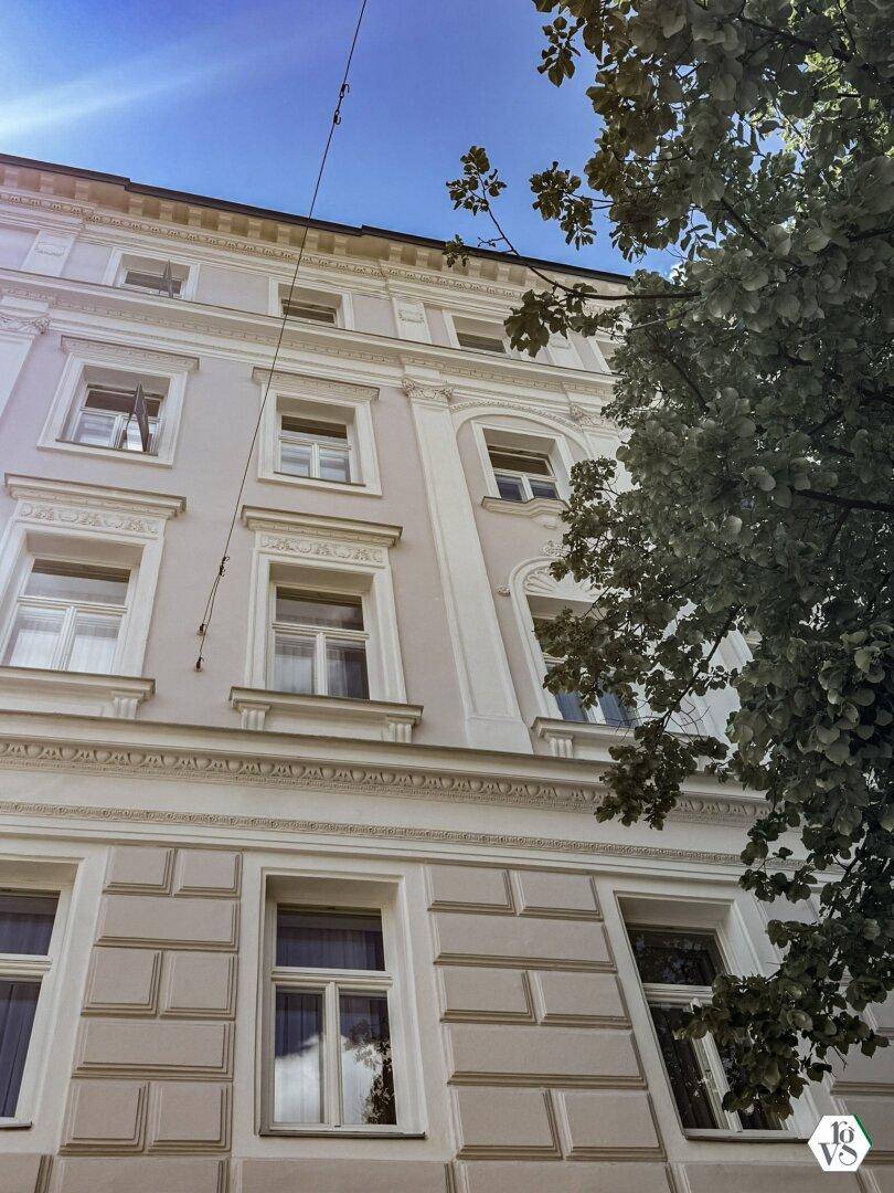 Historische Fassade eines Gebäudes mit verzierten Details und hohen Fenstern.