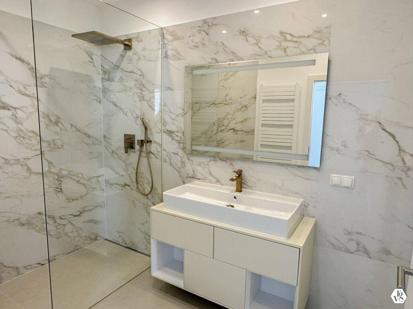 Luxuriöses Badezimmer mit begehbarer Dusche, Einzelwaschbecken und Marmorfliesen.