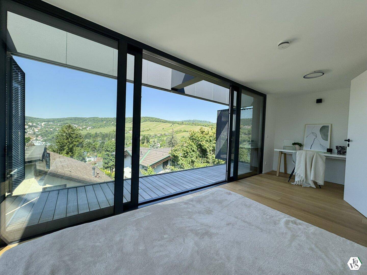 Schlafzimmer mit großen Fenstern, Holzboden und weitem Blick auf Weinberge und Landschaft.