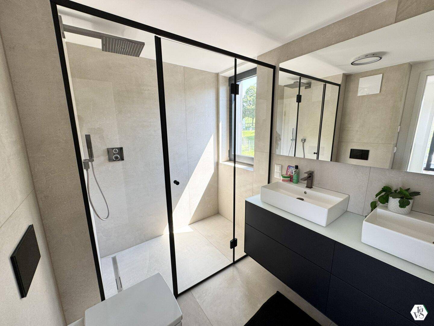 Modernes Badezimmer mit großer begehbarer Dusche, Doppelwaschbecken und Fenster.