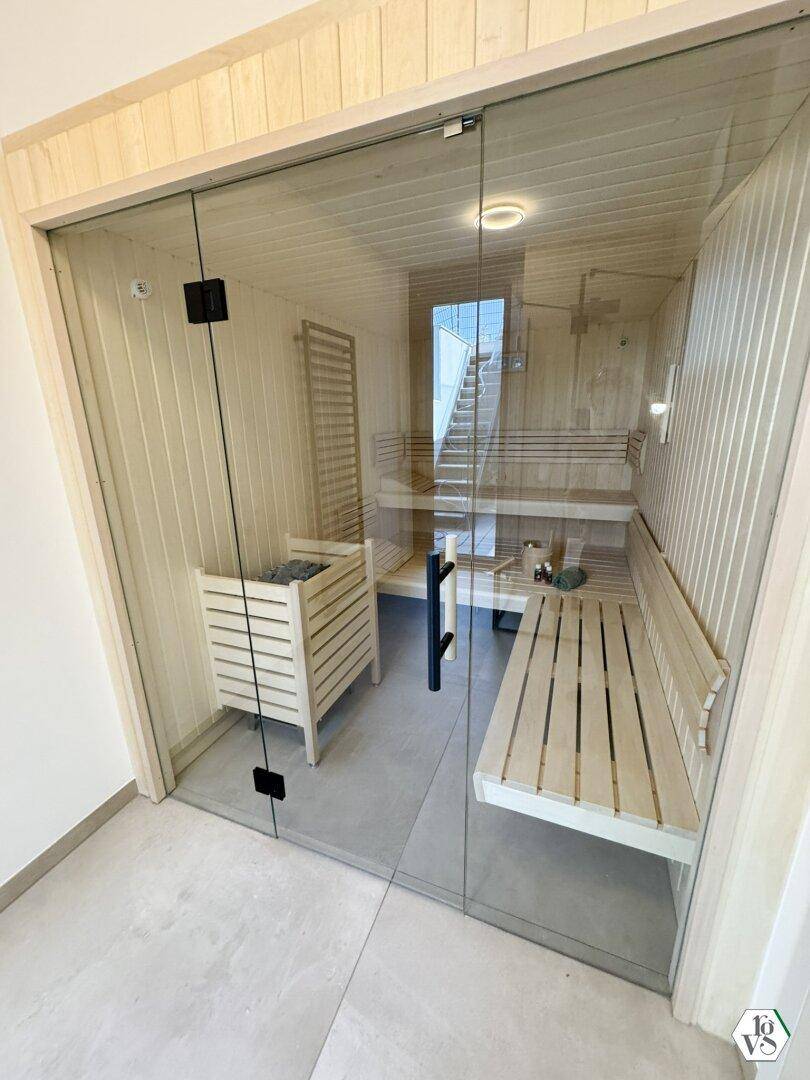 Moderne Sauna mit Holzbänken und Glasfront für entspannende Momente.