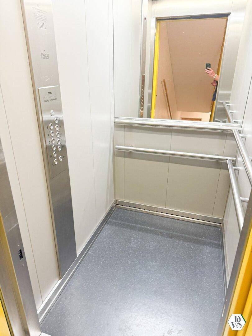 Geräumiger Aufzug mit Edelstahlbedienfeld und Haltegriffen für Barrierefreiheit.