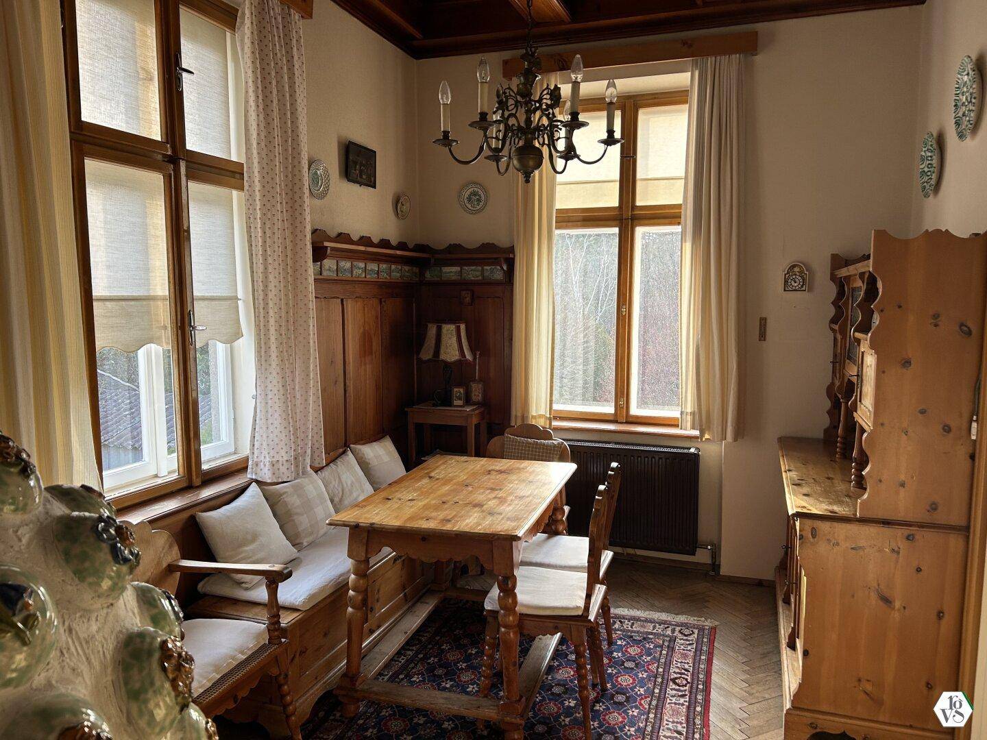 Gemütliches Esszimmer im alpinen Stil mit Holztäfelung, Kachelofen und traditionellen Möbeln.