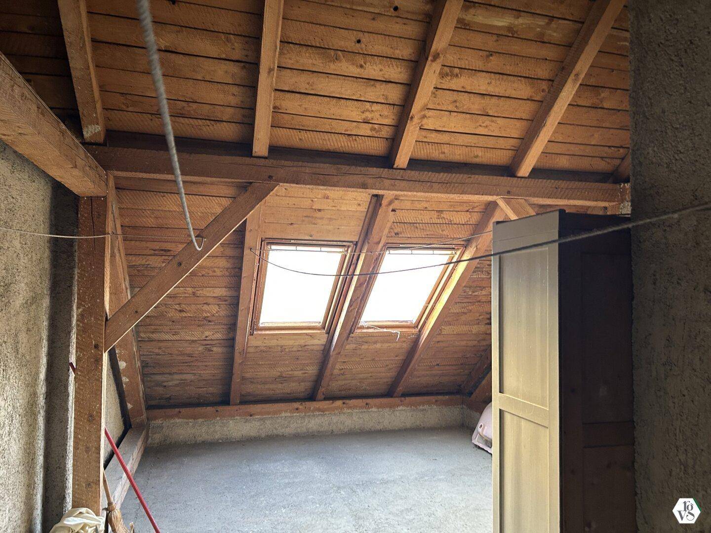 Dachbodenbereich mit sichtbarer Holzkonstruktion und zwei Dachfenstern für natürliches Licht.