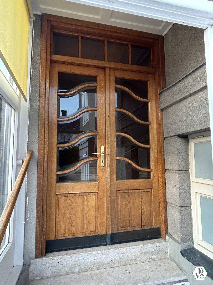 Klassische Holztür mit geschwungenen Glaseinsätzen und einem traditionellen Türgriff.