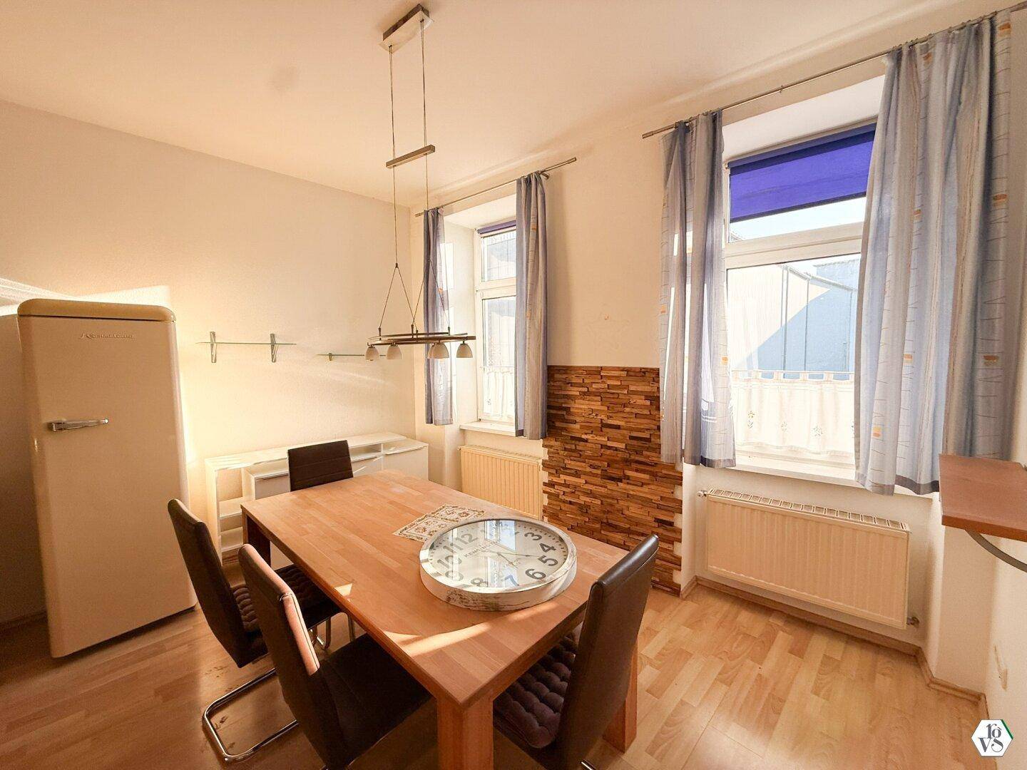 Gemütlicher Essbereich mit Holztisch, Stühlen und einem Retro-Kühlschrank.