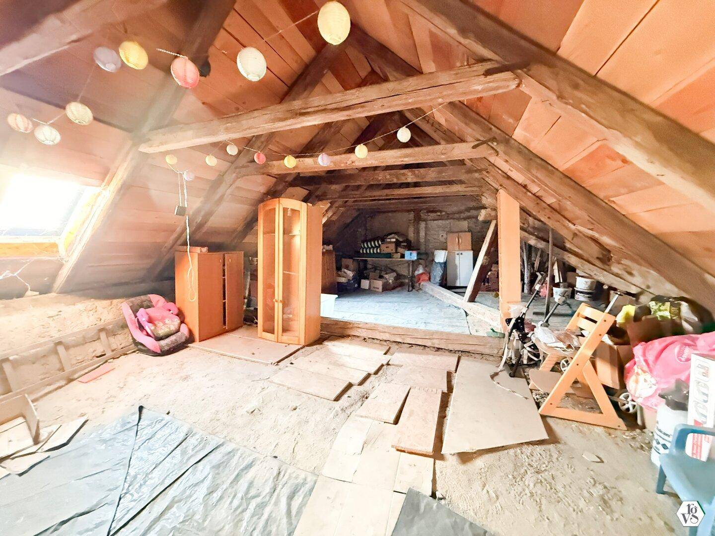 Unausgebauter Dachboden mit sichtbaren Holzbalken und Stauraum.