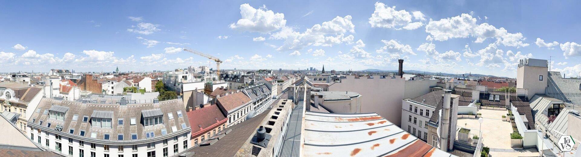 Panoramablick über die Dächer der Stadt mit weitem Horizont und blauem Himmel.