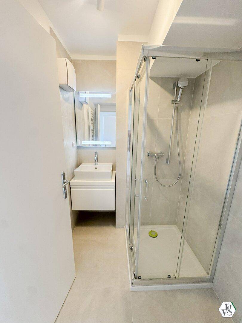 Modernes Badezimmer mit Duschkabine, Waschbecken und Spiegelschrank in hellen Farbtönen.
