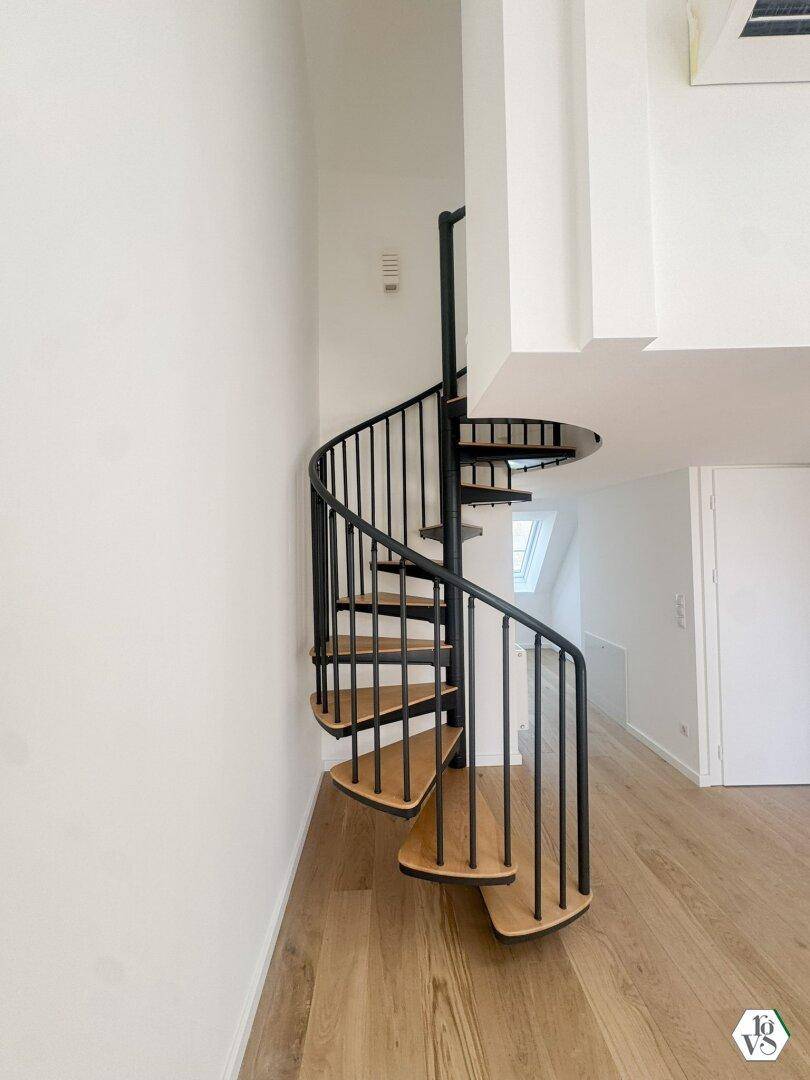 Elegante Wendeltreppe aus Holz und Metall, die die Ebenen des modernen Wohnraums verbindet.