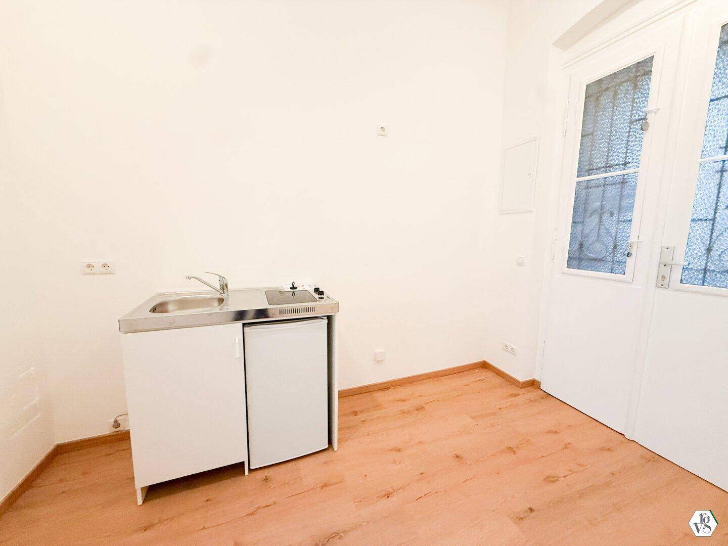 Kleiner Raum mit integrierter Küchenzeile und Doppeltür, ideal für ein Studio-Apartment.