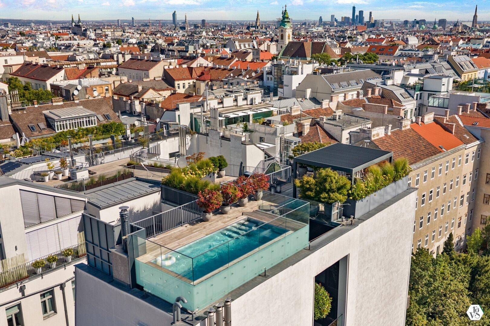 Luftaufnahme eines modernen Gebäudes mit Dachterrasse und Pool in der Stadt.