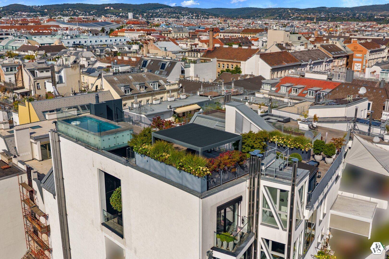 Vogelperspektive auf ein Gebäude mit begrünter Dachterrasse und Pool.