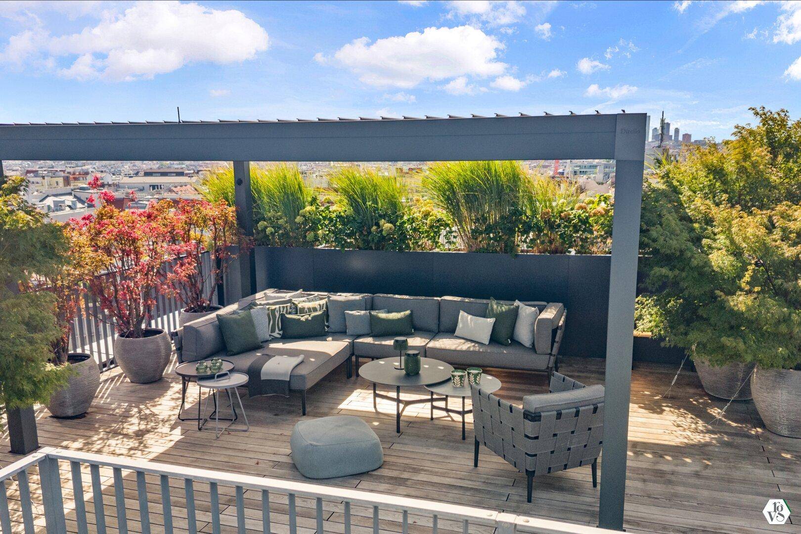 Gemütlicher Lounge-Bereich auf der Dachterrasse mit Stadtblick und Pflanzen.
