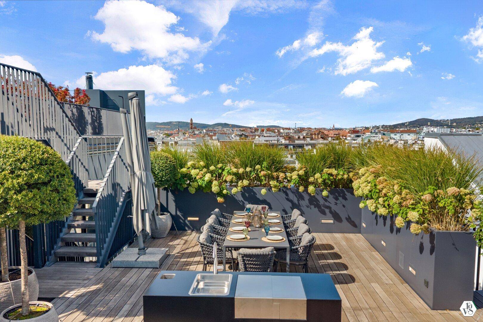Essbereich und Außenküche auf der Dachterrasse mit Panoramablick über die Stadt.