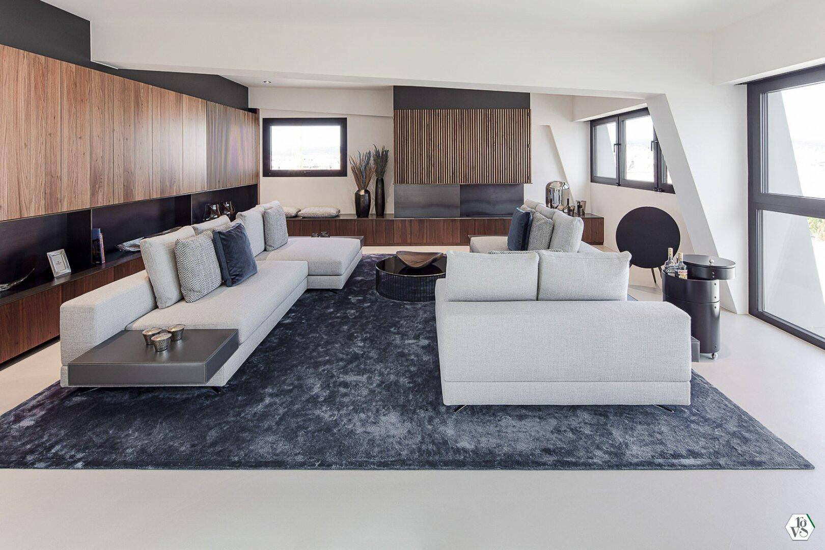 Geräumiges Wohnzimmer mit bequemen Sofas, Holzwänden und dunklem Teppich.