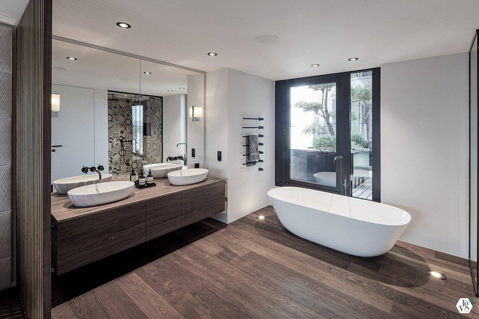 Luxuriöses Badezimmer mit freistehender Badewanne, Doppelwaschbecken und Fenster.