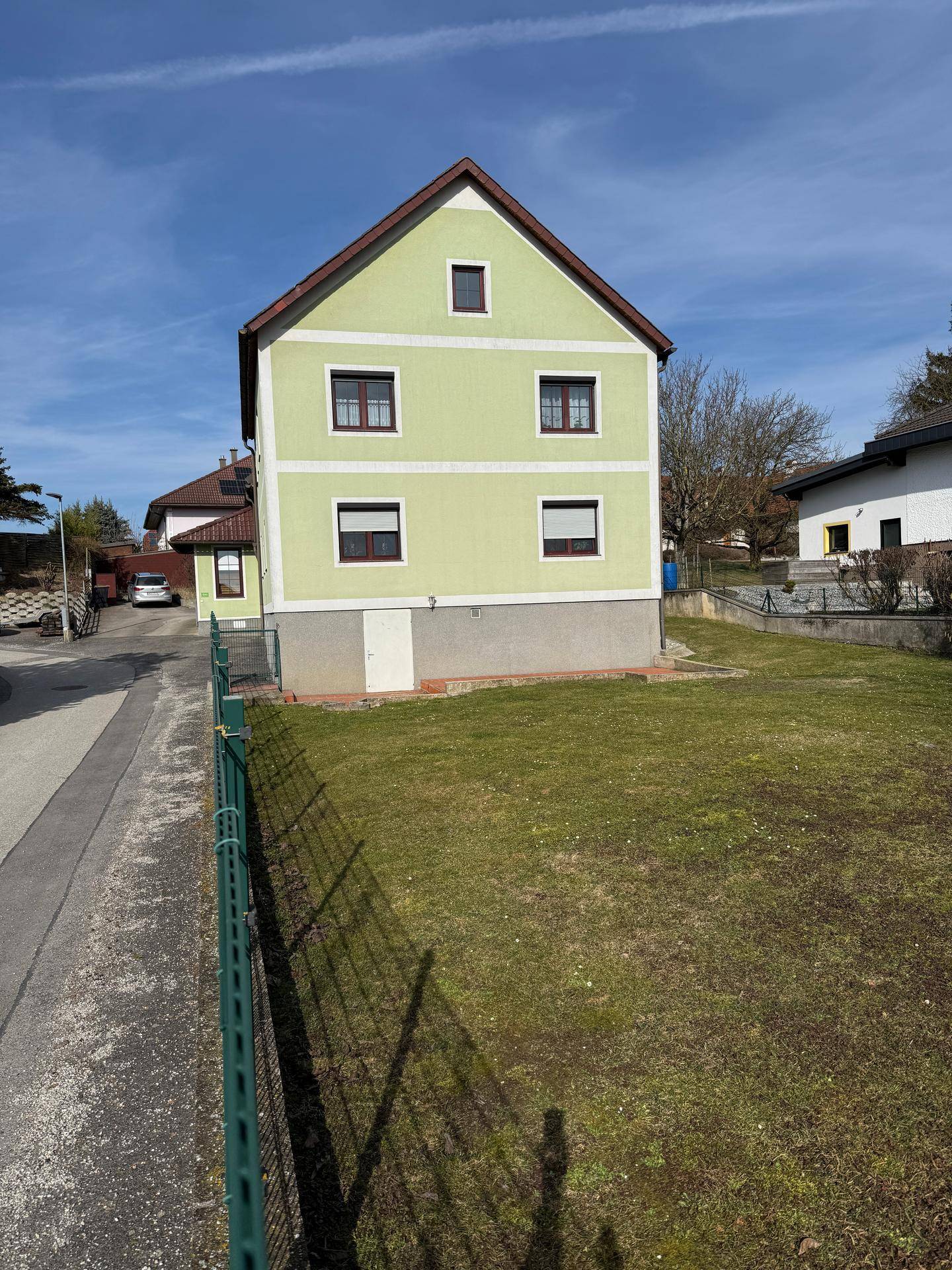 Seitenansicht des Wohnhauses mit großer Rasenfläche und Blick auf die Umgebung.