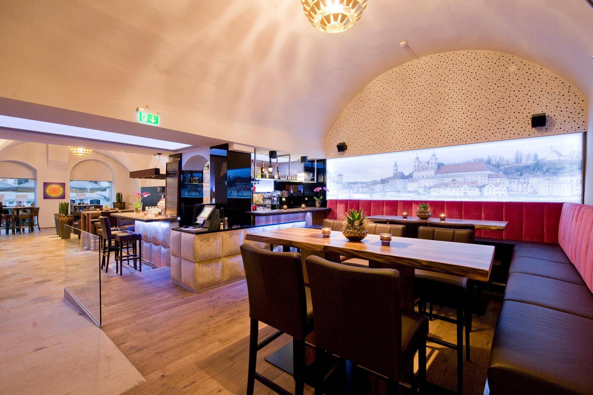 Moderne Bar und Lounge-Bereich mit Holzböden, bequemen Sitzgelegenheiten und einer beleuchteten Wanddekoration.